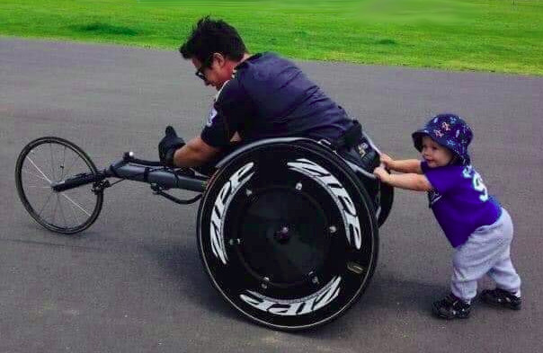 Petit enfant poussant un fauteuil roulant de course
